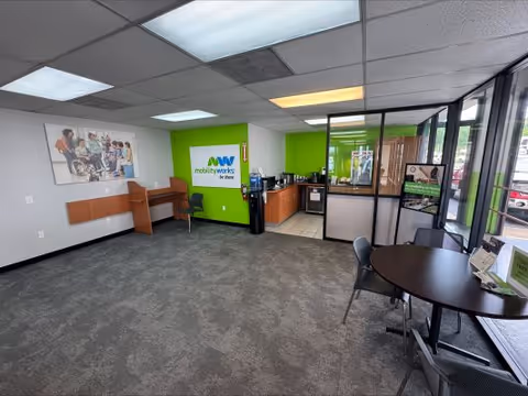 Interior lobby area with a green accent wall, reception counter, and seating near glass partitions.