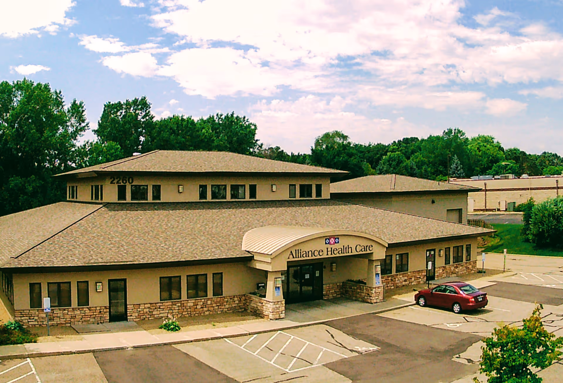 Exterior view of Alliance Health Care building with parking lot and clear sky.