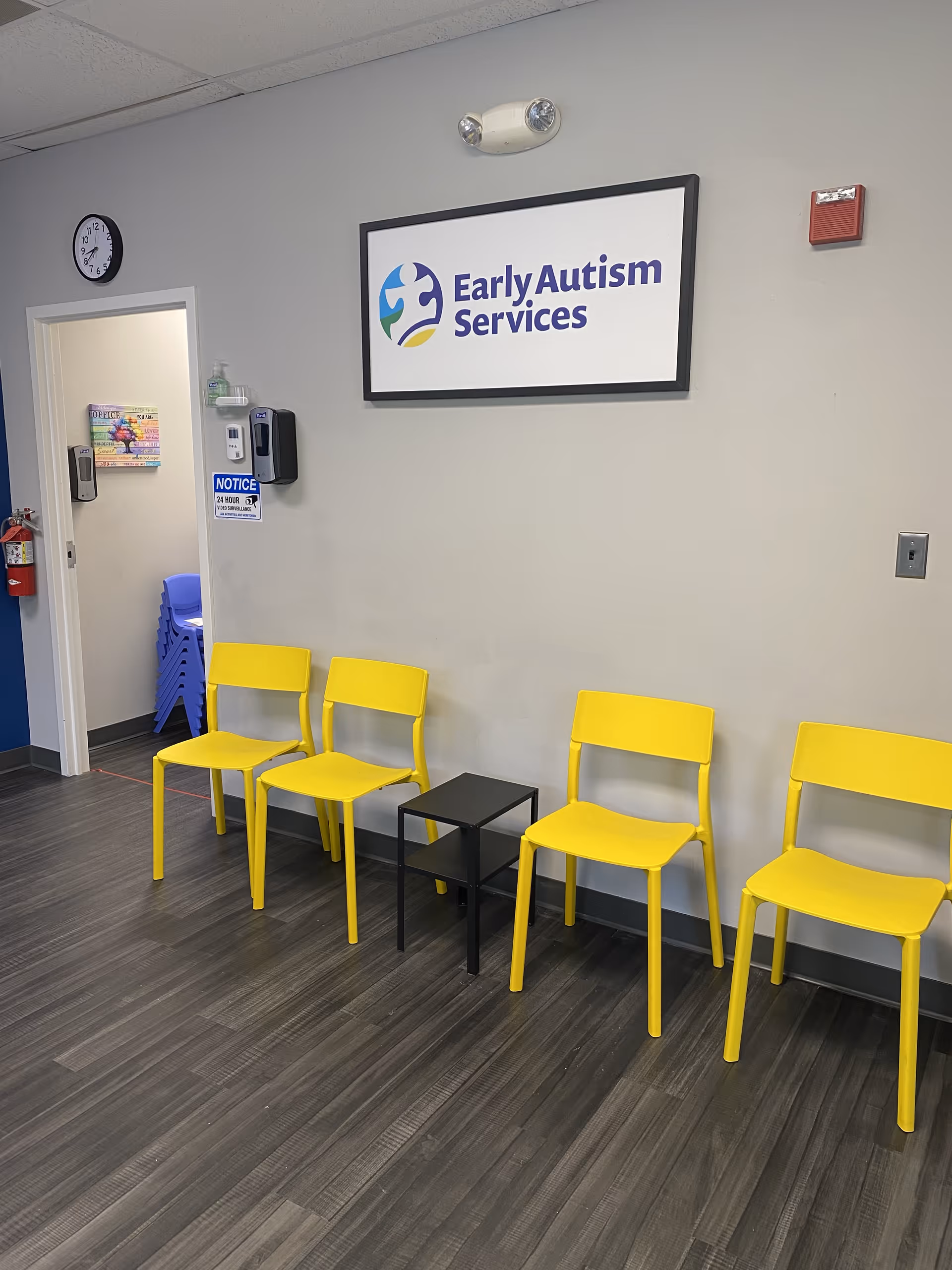 Waiting area with yellow chairs along a gray wall and Early Autism Services sign.