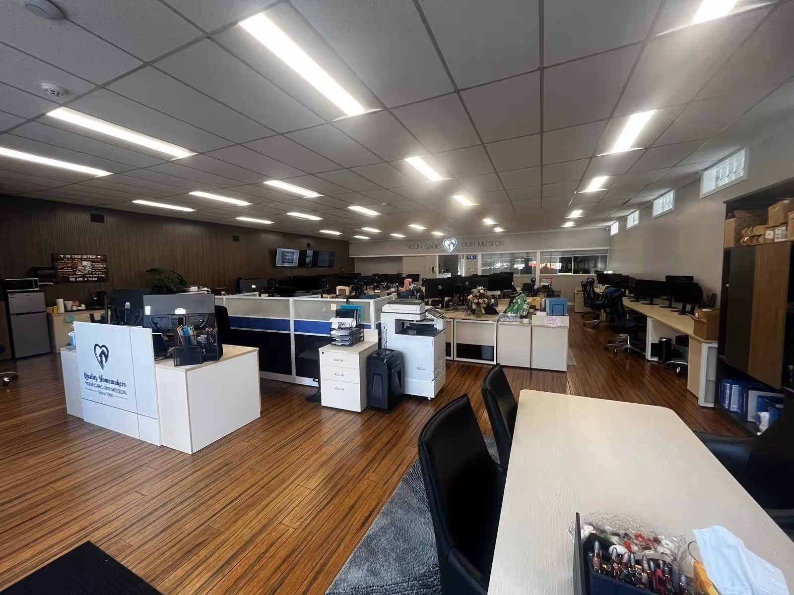 Open interior office area with cubicles, desks, and a reception at Quality Homemakers.