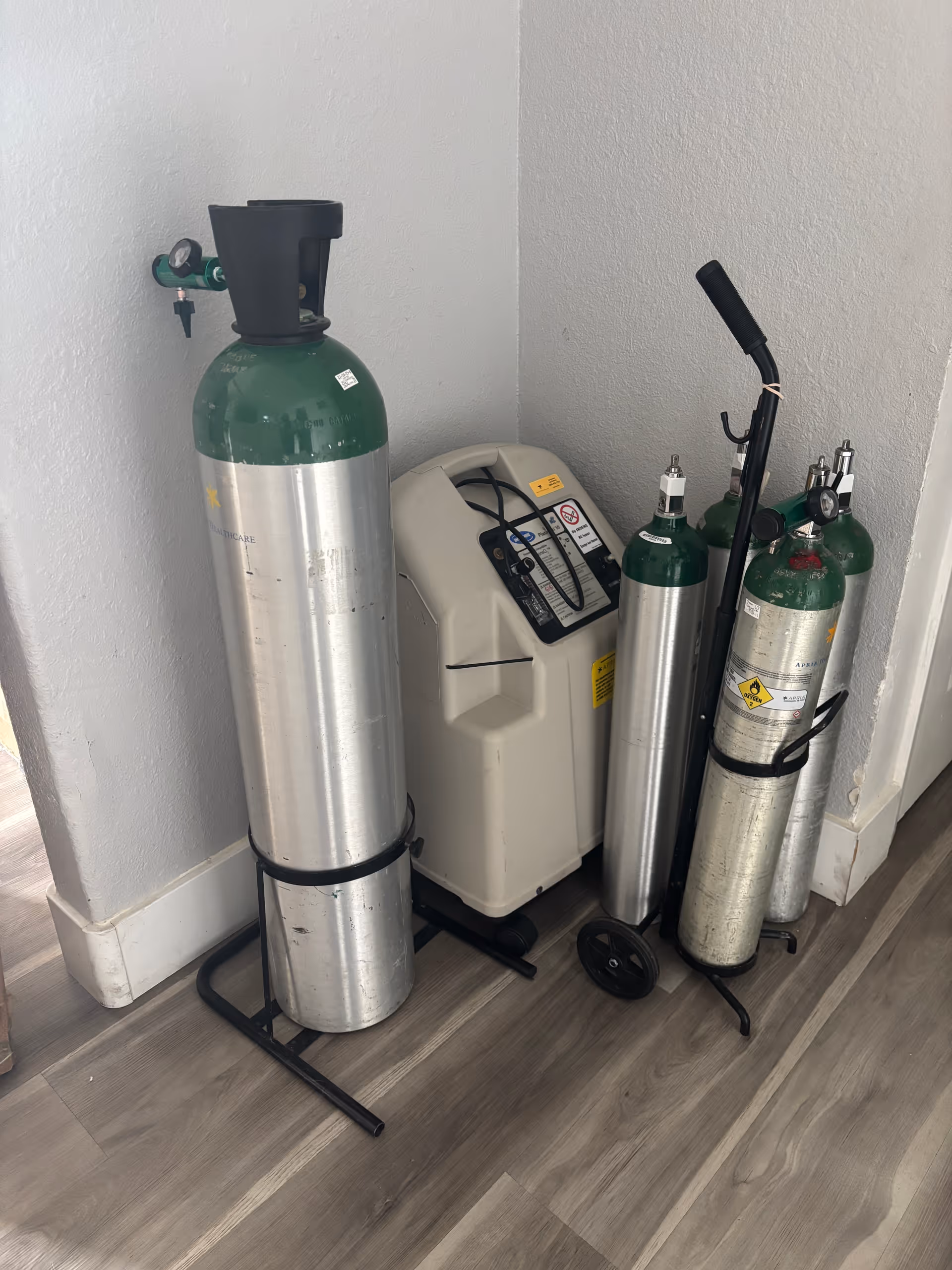 Oxygen tanks and a portable medical device stored beside a wall corner.