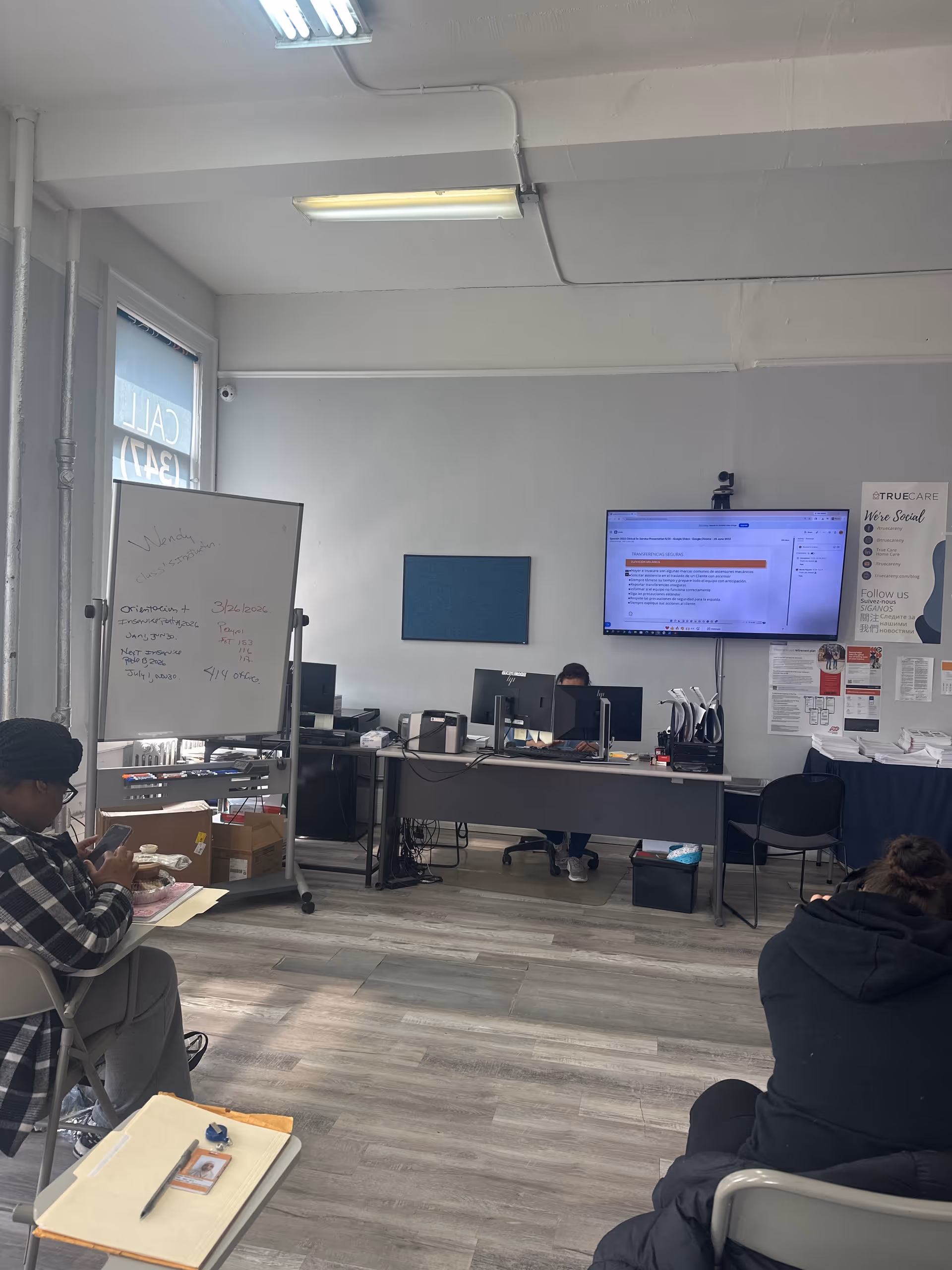 A bright office space in a care facility with desks, computers, and a whiteboard.