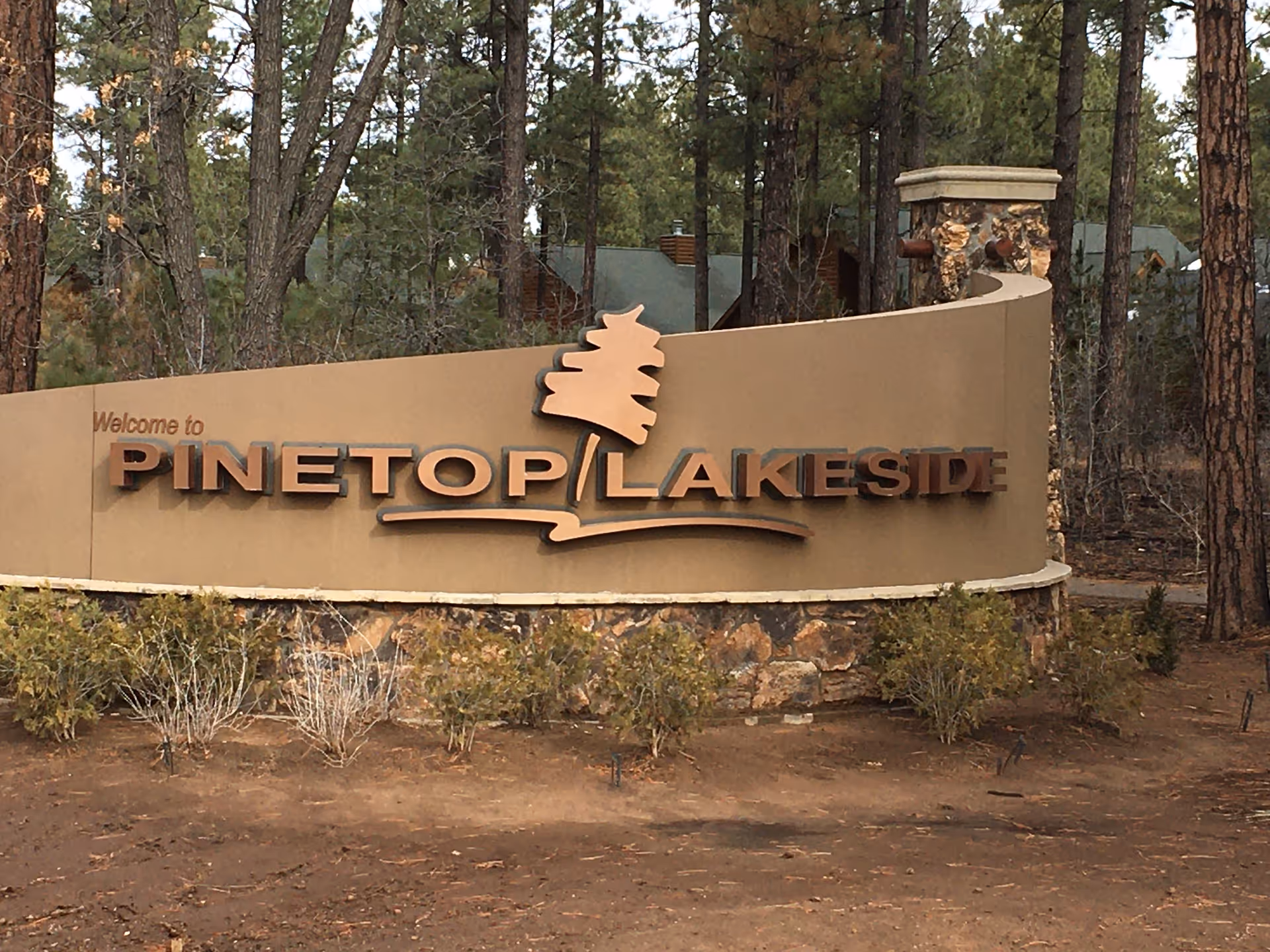 Exterior entrance sign reading PINE TOP / LAKESIDE among trees.