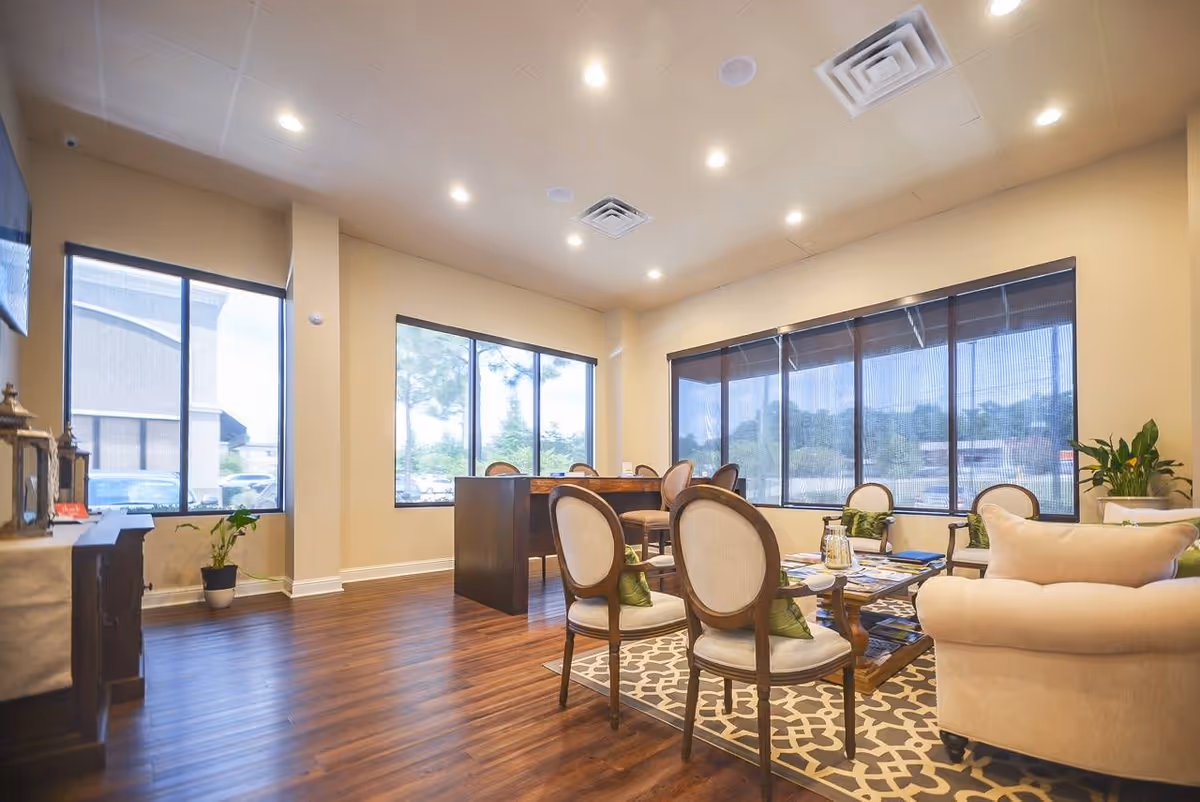 Bright senior living common area with modern seating, a coffee table, and large windows.