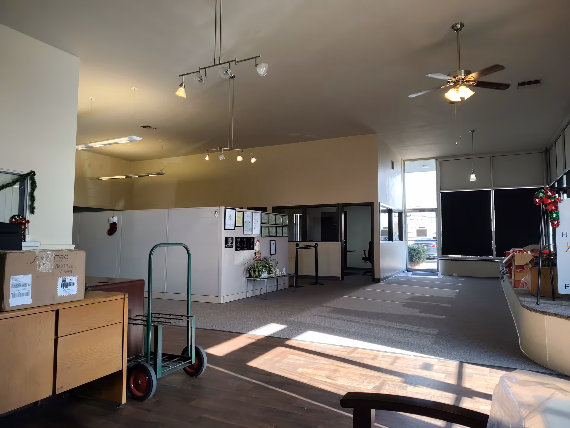A spacious interior lobby with a cart, desk, cubicles, and holiday decor.