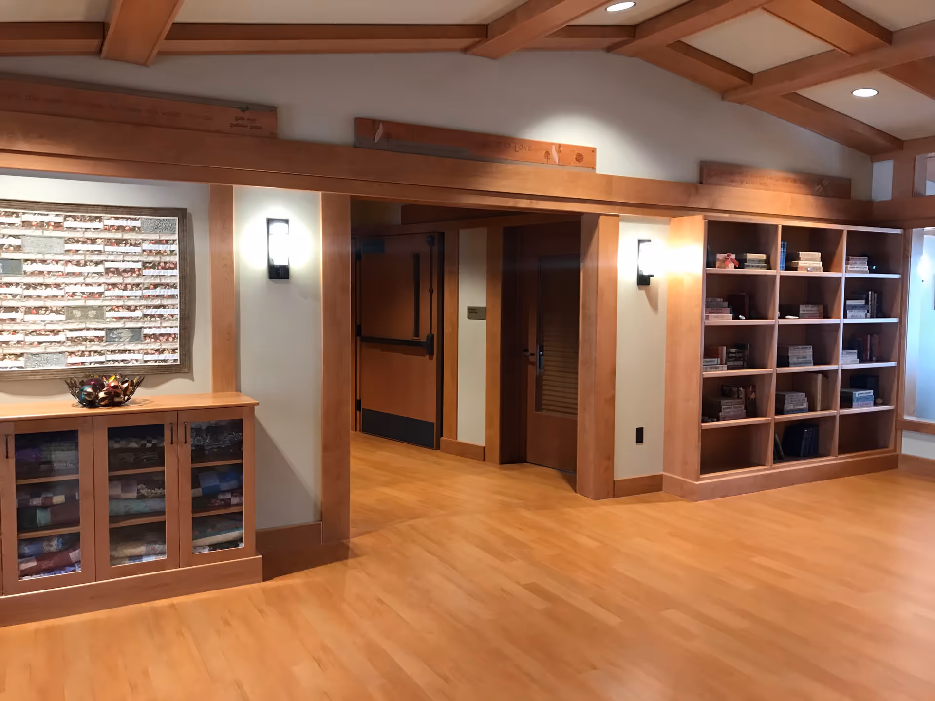 Wood-paneled interior lobby with bookshelves, a cabinet, and warm lighting.