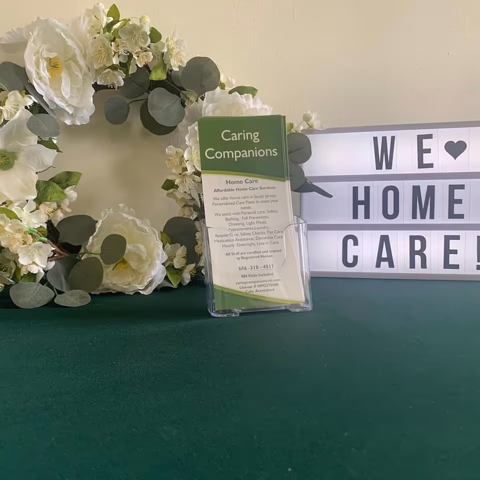Floral arrangement and Caring Companions Home Care sign on a green table.
