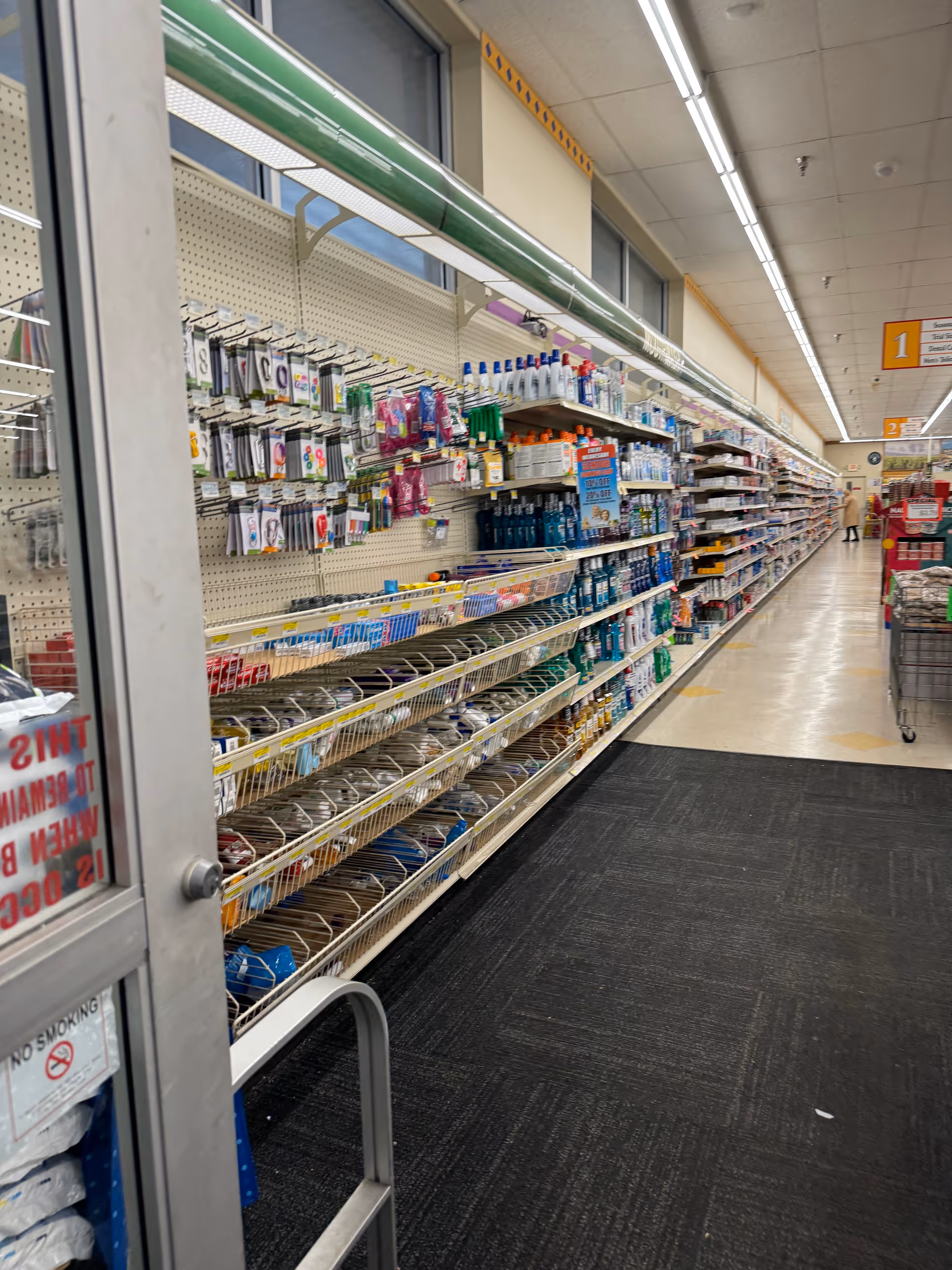 Wide supermarket aisle with shelves stocked with toiletries and household items inside Discount Drug Mart.