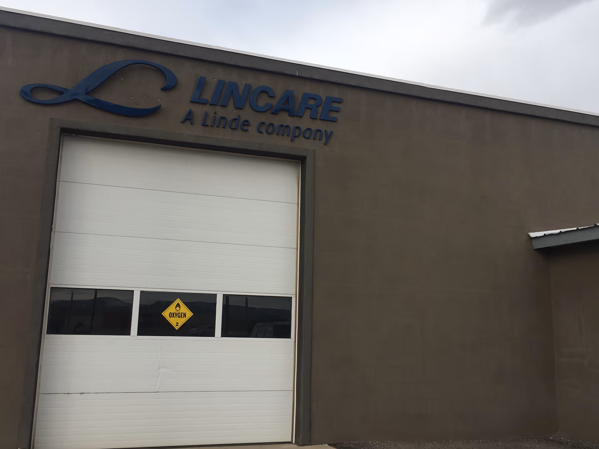 Exterior view of Lincare facility front with large white garage door and blue logo sign.
