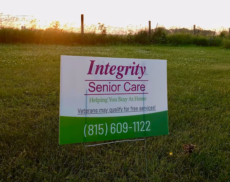 A large Integrity Senior Care sign stands in a sunlit grassy field.