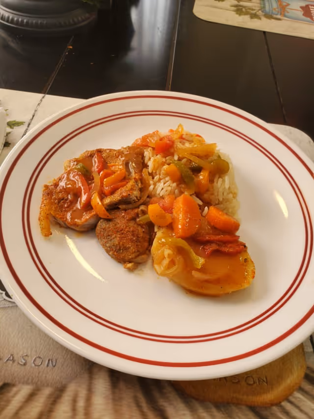 Plate of mixed roasted meat, rice, and vegetables on a white plate.