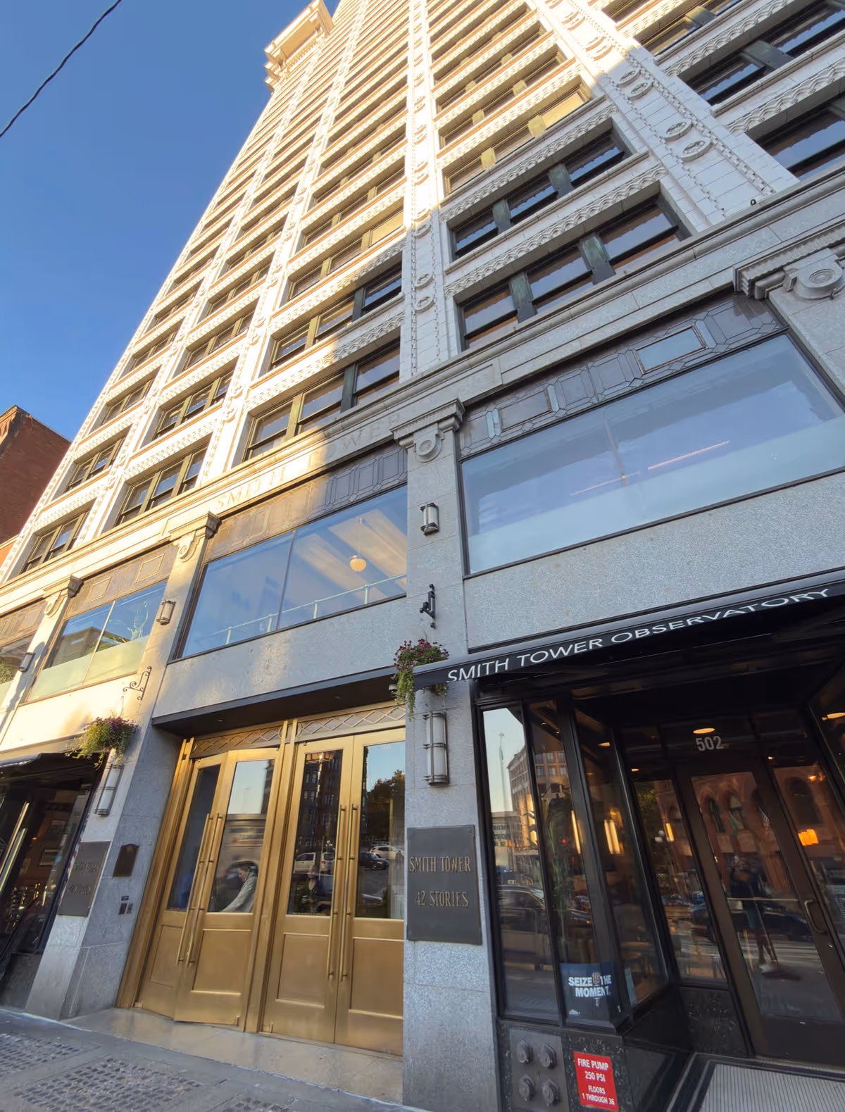 Tall, ornate urban building with gold doors and large storefront windows at street level.