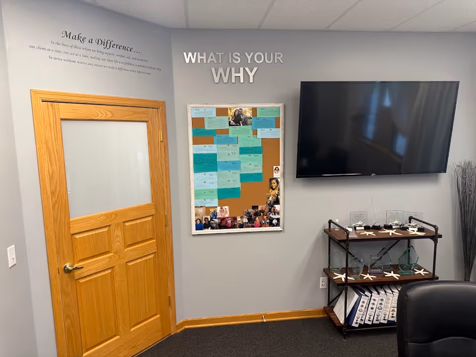 Interior facility lobby with a wooden door, bulletin board, TV, and a shelf display.