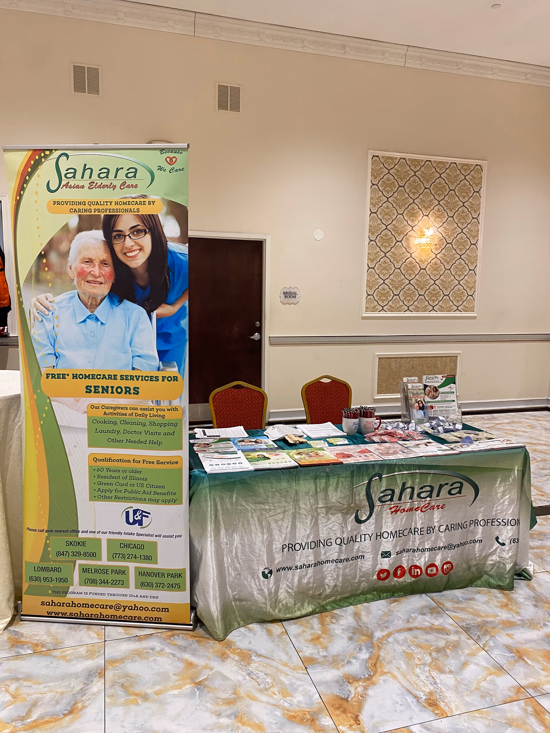 Indoor Sahara Home Care banner with brochure table in a reception-like area.
