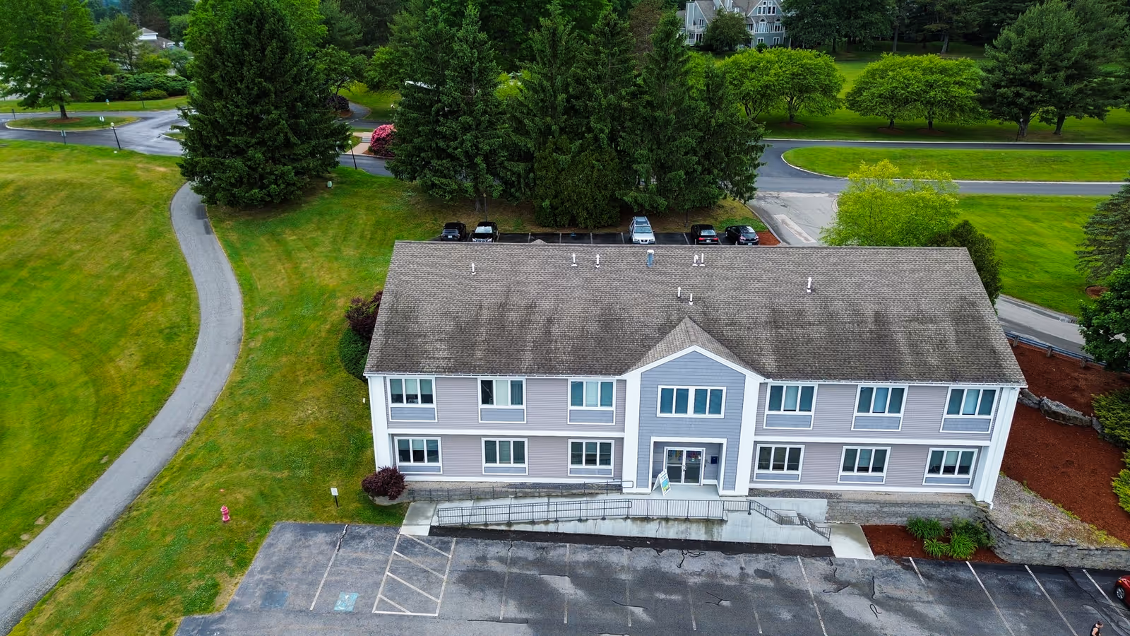 Aerial view of a two-story senior living facility with parking and green grounds.