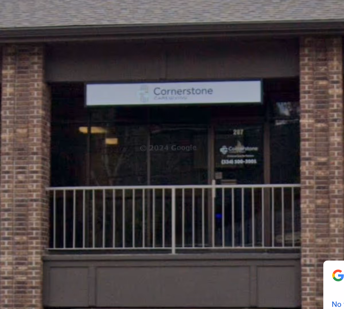 Brick storefront with Cornerstone Caregiving sign above the entrance and railing