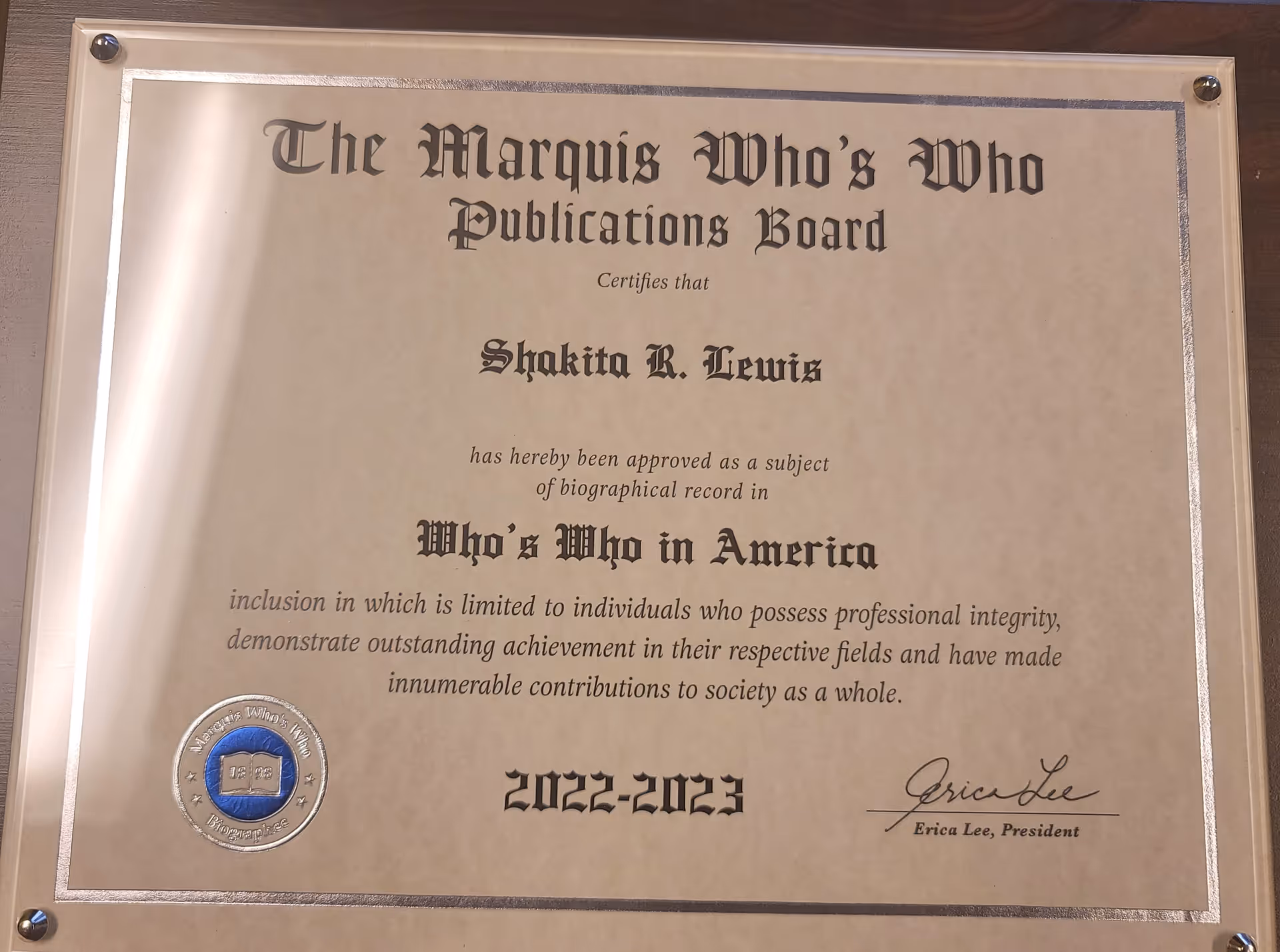 Framed certificate plaque on a wall, titled The Marquis Who's Who Publications Board.