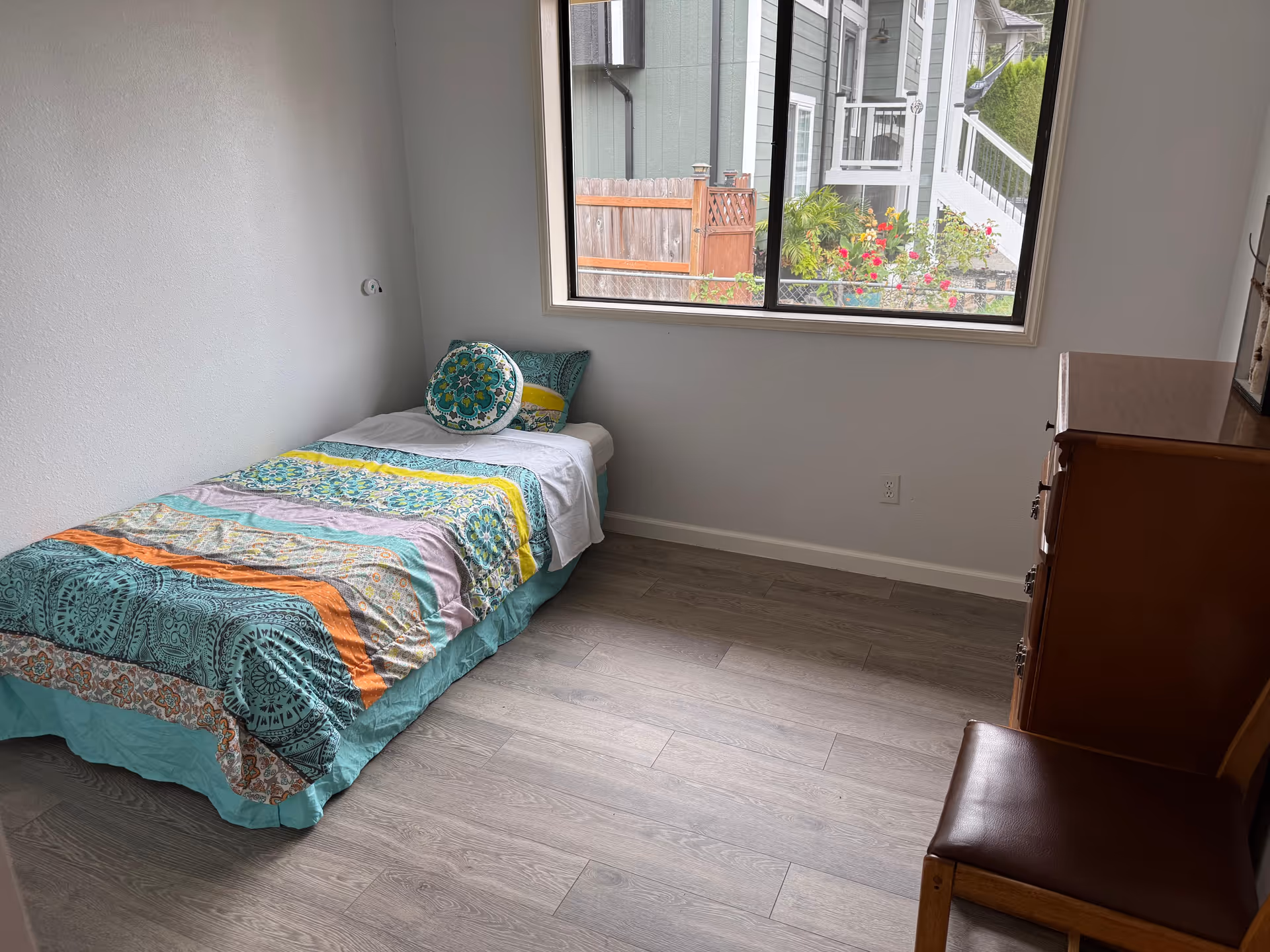Small bedroom with a single bed, dresser, chair, and window view.