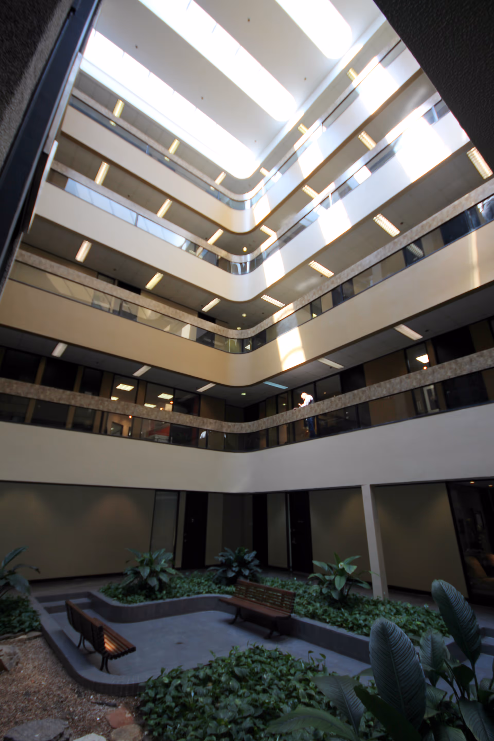 Interior atrium with curved balconies, walkways, skylight, and a central garden.