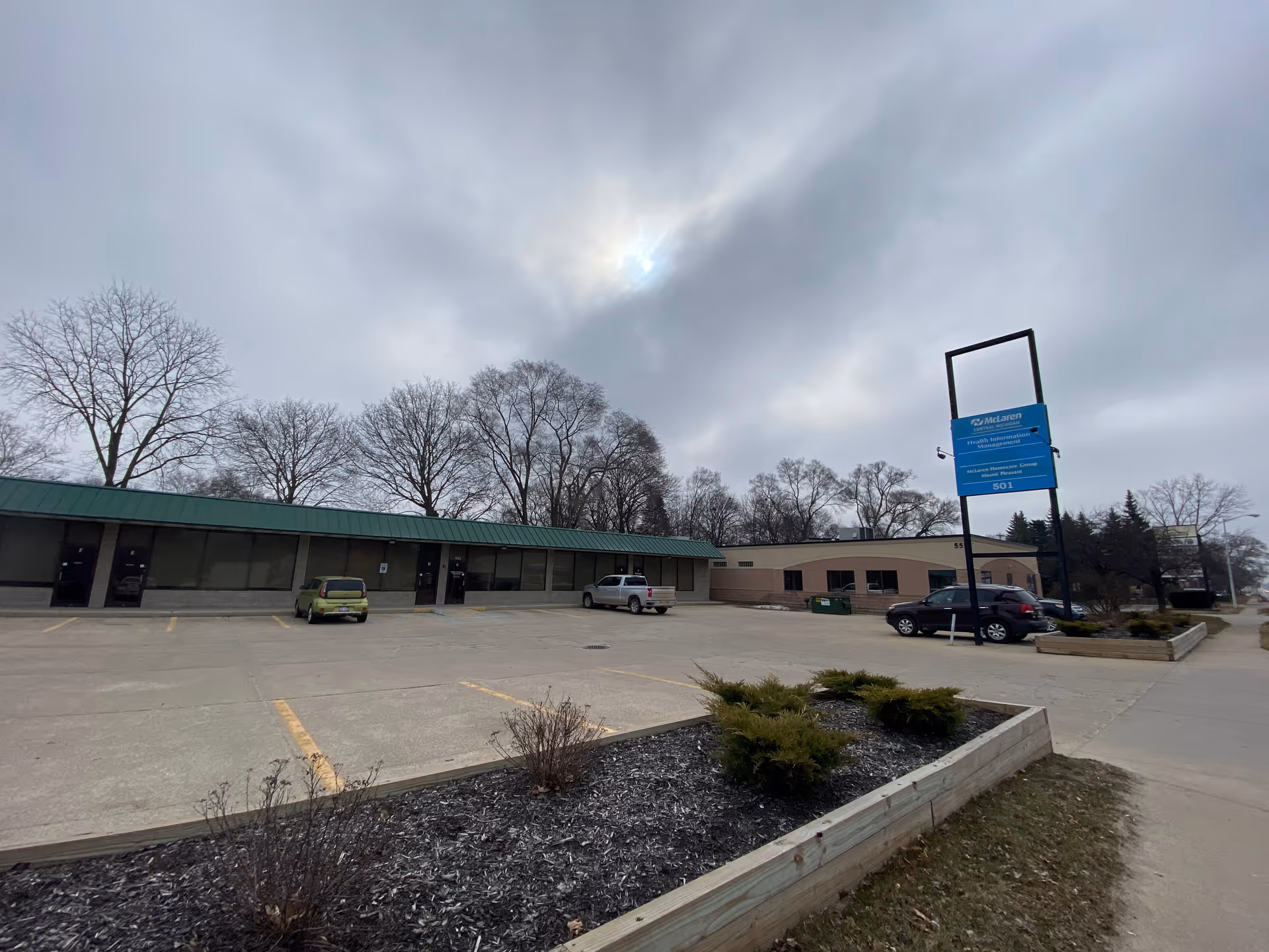 Exterior view of a single-story senior care building with a parking lot and a blue sign.