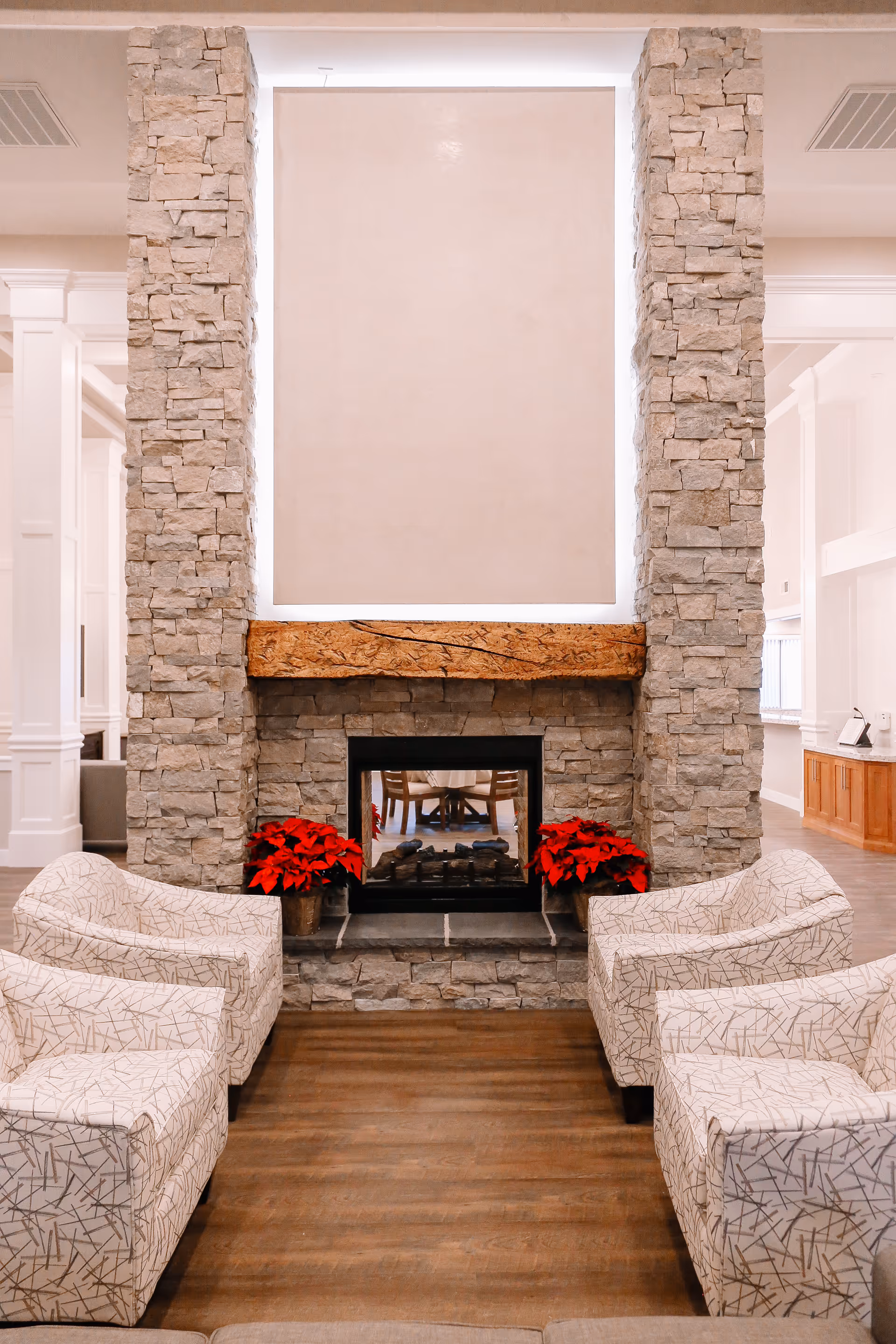 Stone fireplace with a seating area and red poinsettias in a modern living room.