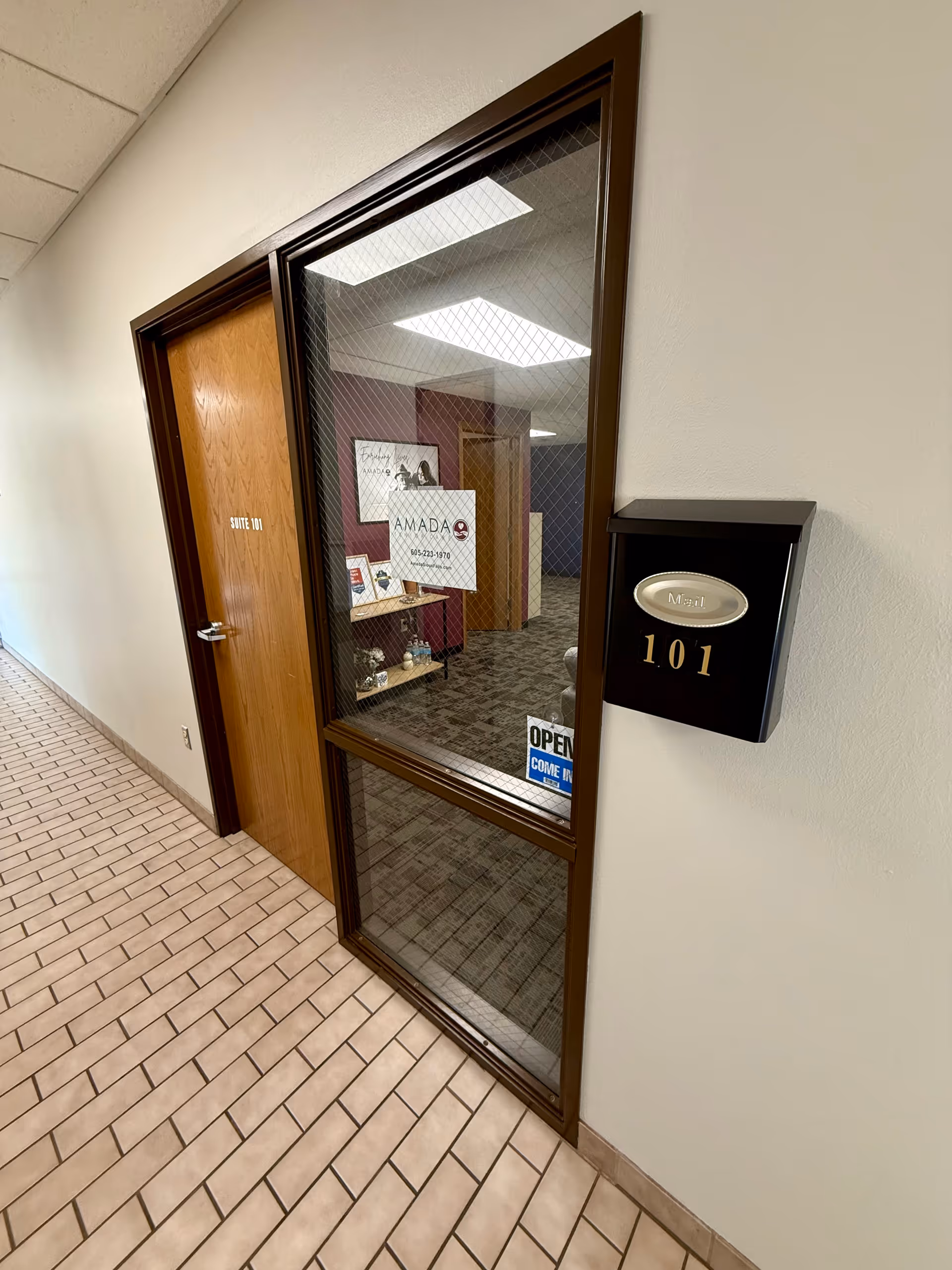 Indoor hallway with glass-front door labeled 101 and Amada Senior Care sign