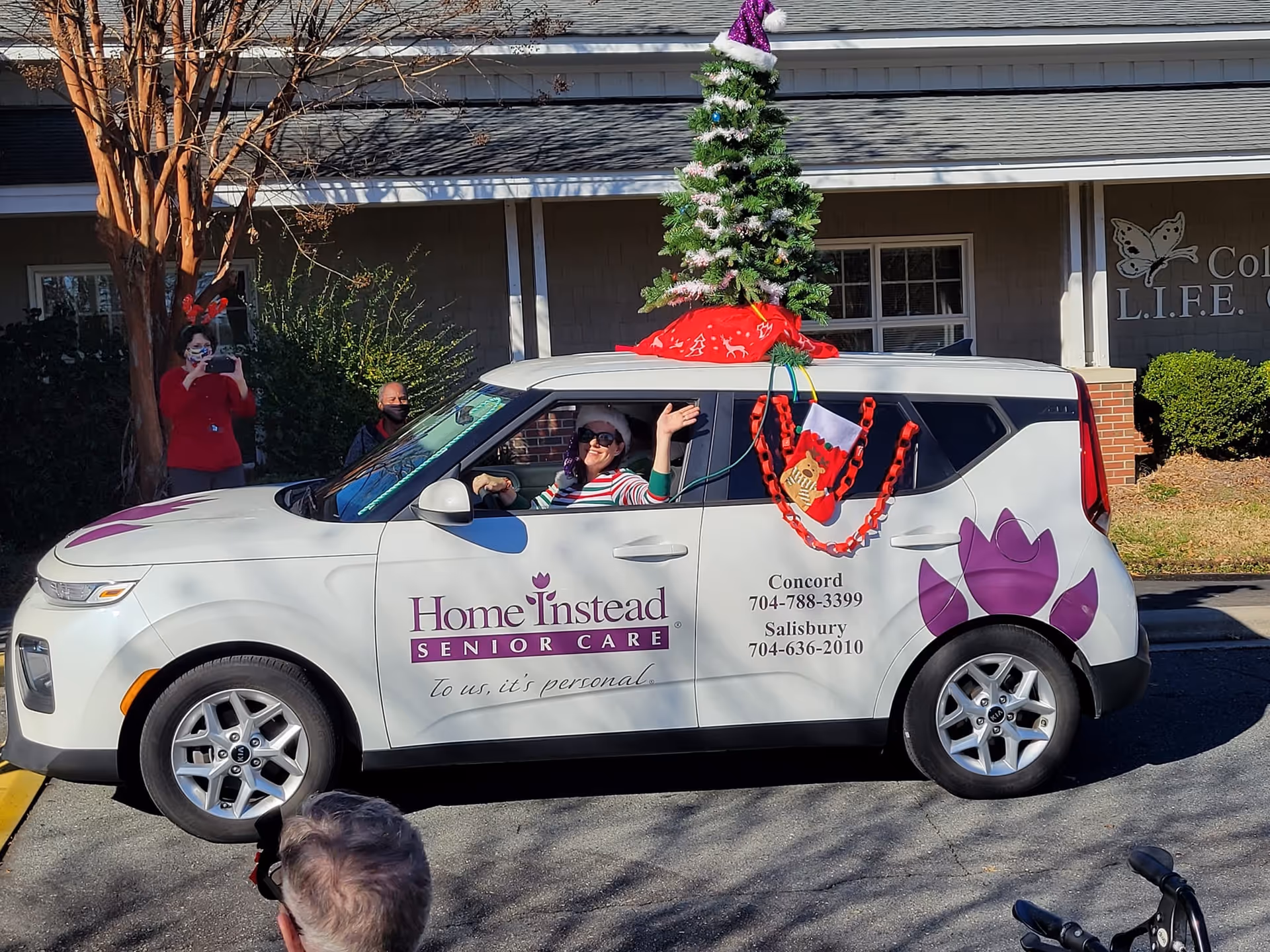 Decorated Home Instead Senior Care van parked outside facility with a Christmas tree on top.