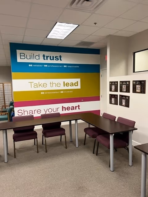 Conference-style meeting room with a long table and colorful wall mural.