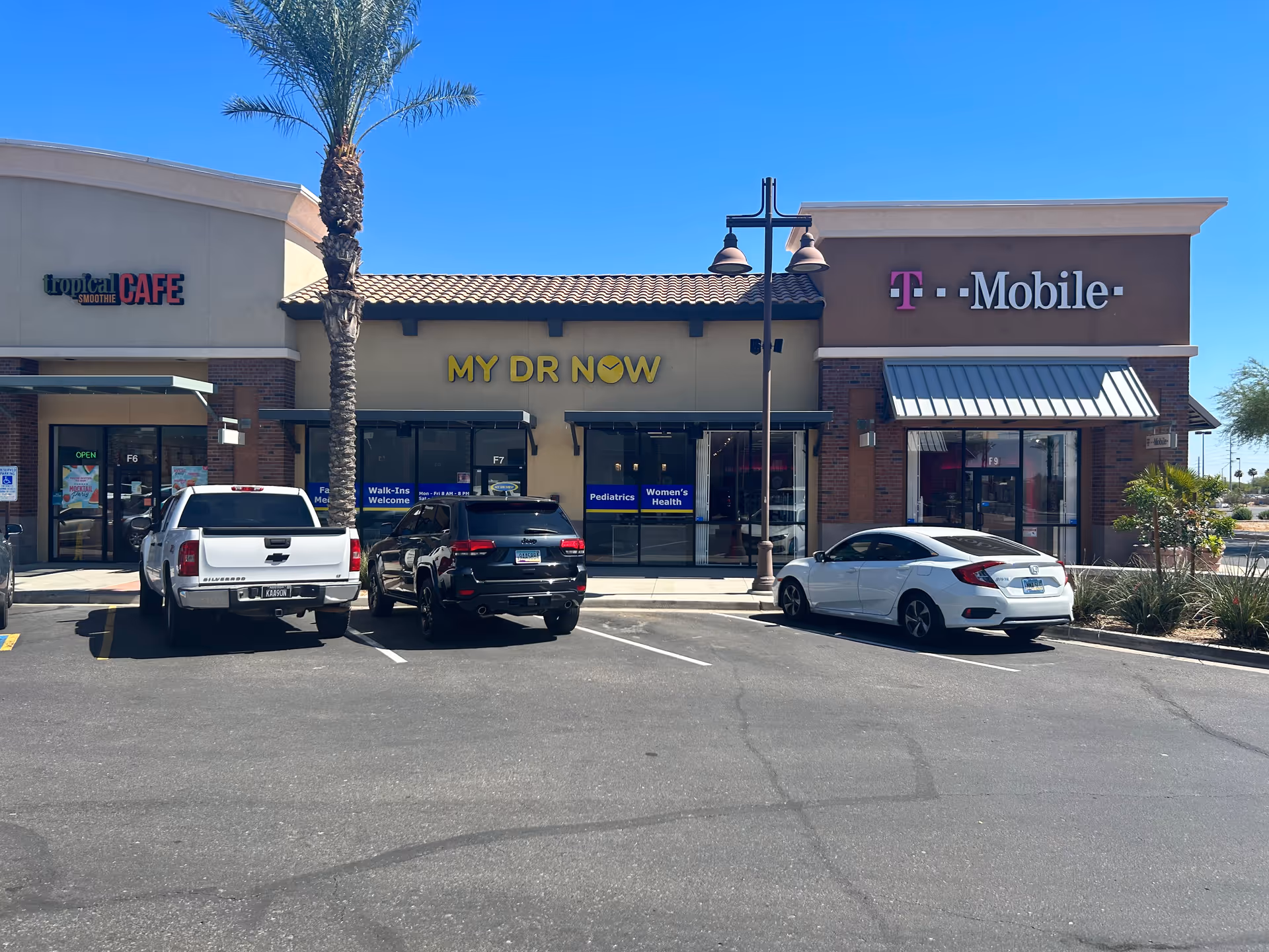 Exterior view of a shopping center with MY DR NOW, T-Mobile, and Tropical Smoothie Cafe.