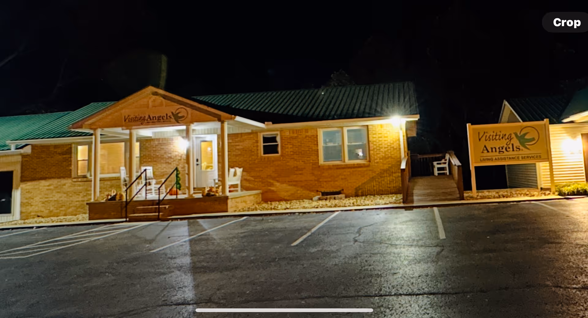 Nighttime exterior of Visiting Angels senior home care facility with brick facade and lit entrance.