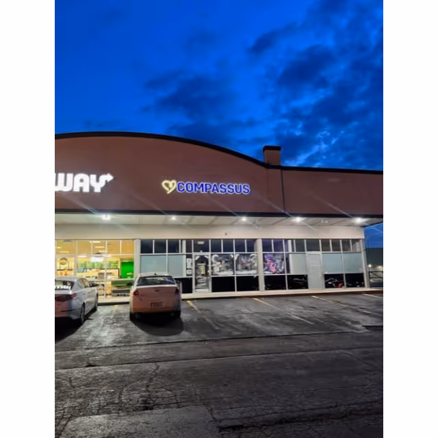 Exterior view of a Compassus building with parking and illuminated signage.