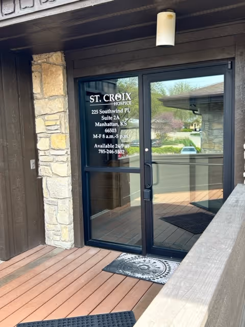 Front entrance of St. Croix Hospice with glass door, address and hours posted on it.