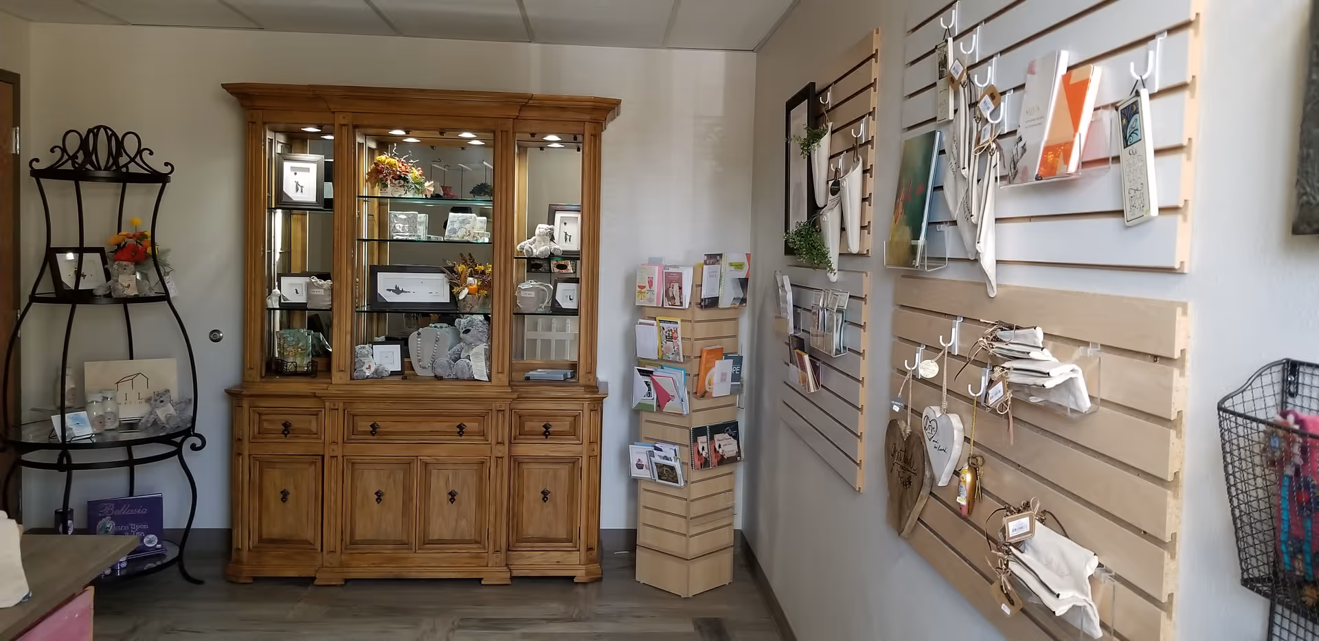 Warm interior gift shop area with wooden cabinet, display shelves, and wall card racks.