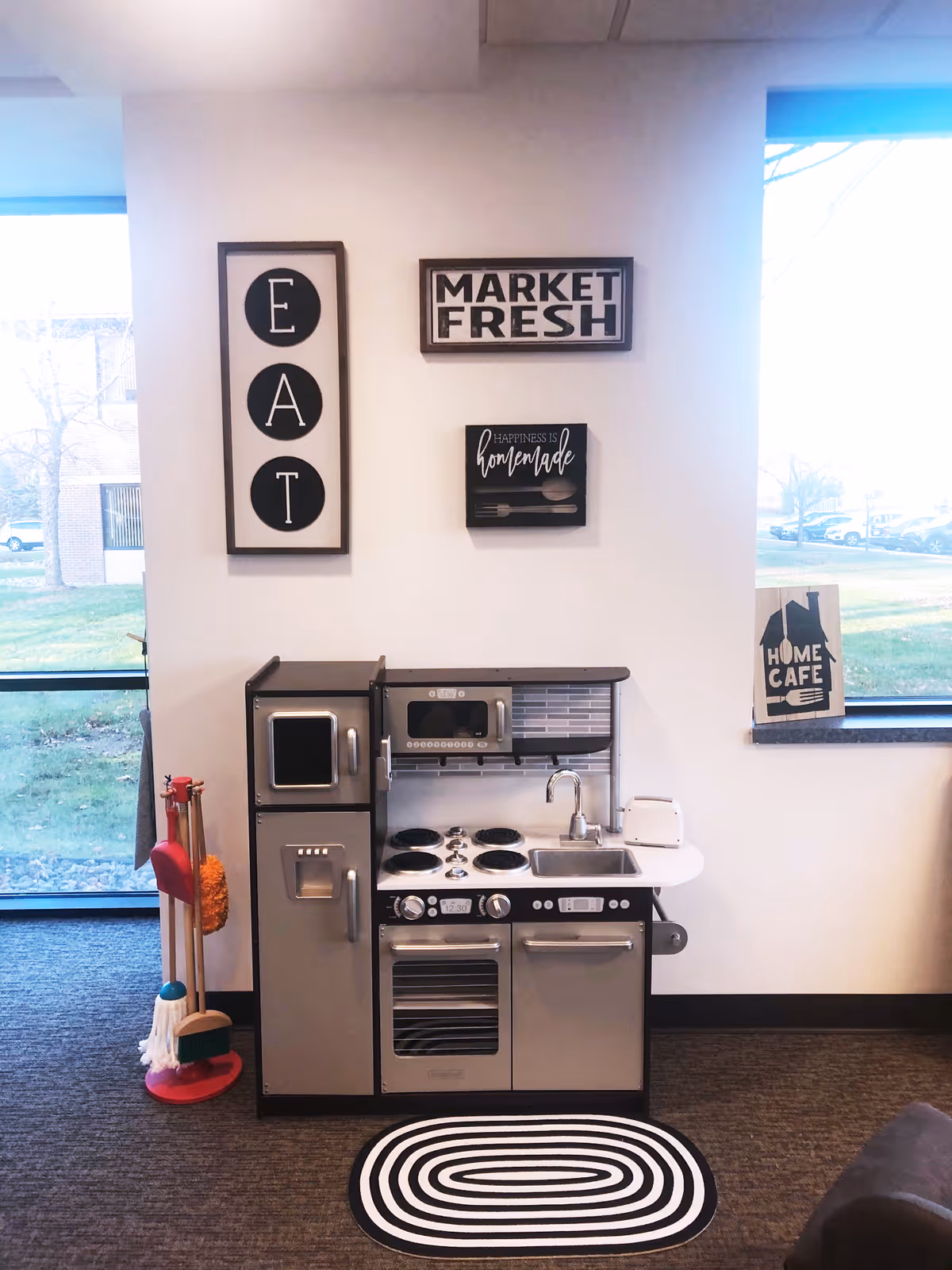 A play kitchen setup with mini appliances and wall decor in a bright interior.