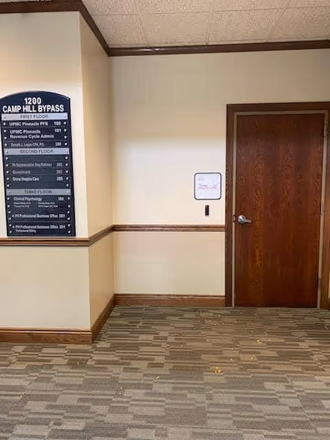 Interior hallway with a wooden door and wall-mounted directory sign.