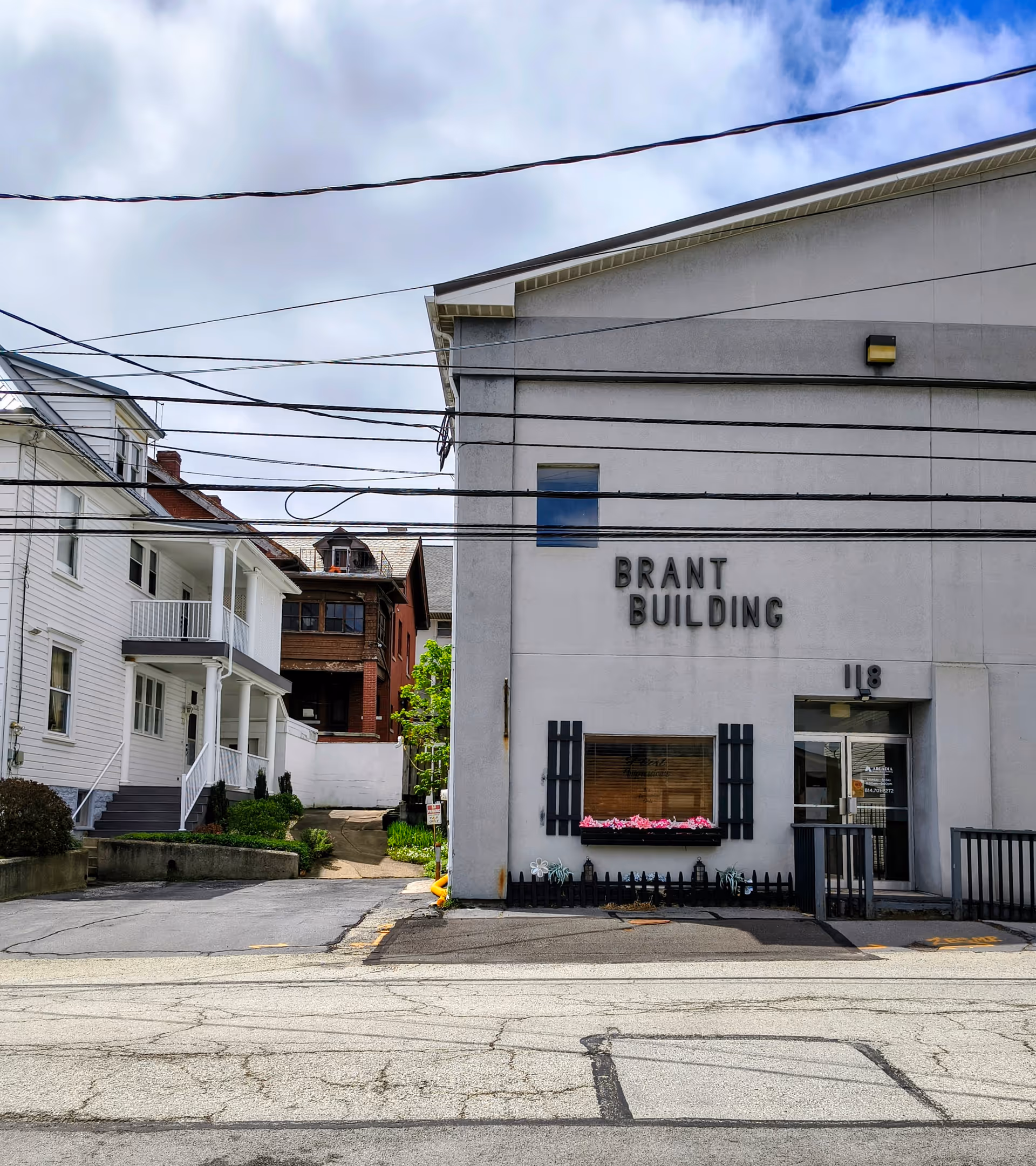Street view of a white building labeled BRANT BUILDING with neighboring homes.