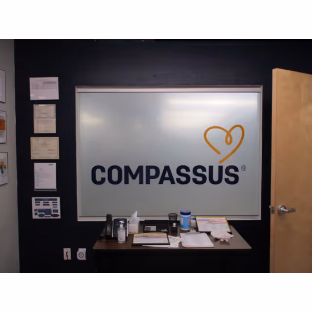 Reception area featuring a large Compassus sign on a frosted glass panel.