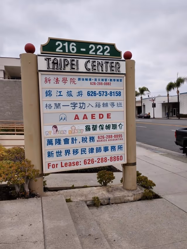 A tall, multi-panel outdoor sign for Taipei Center on a sidewalk.