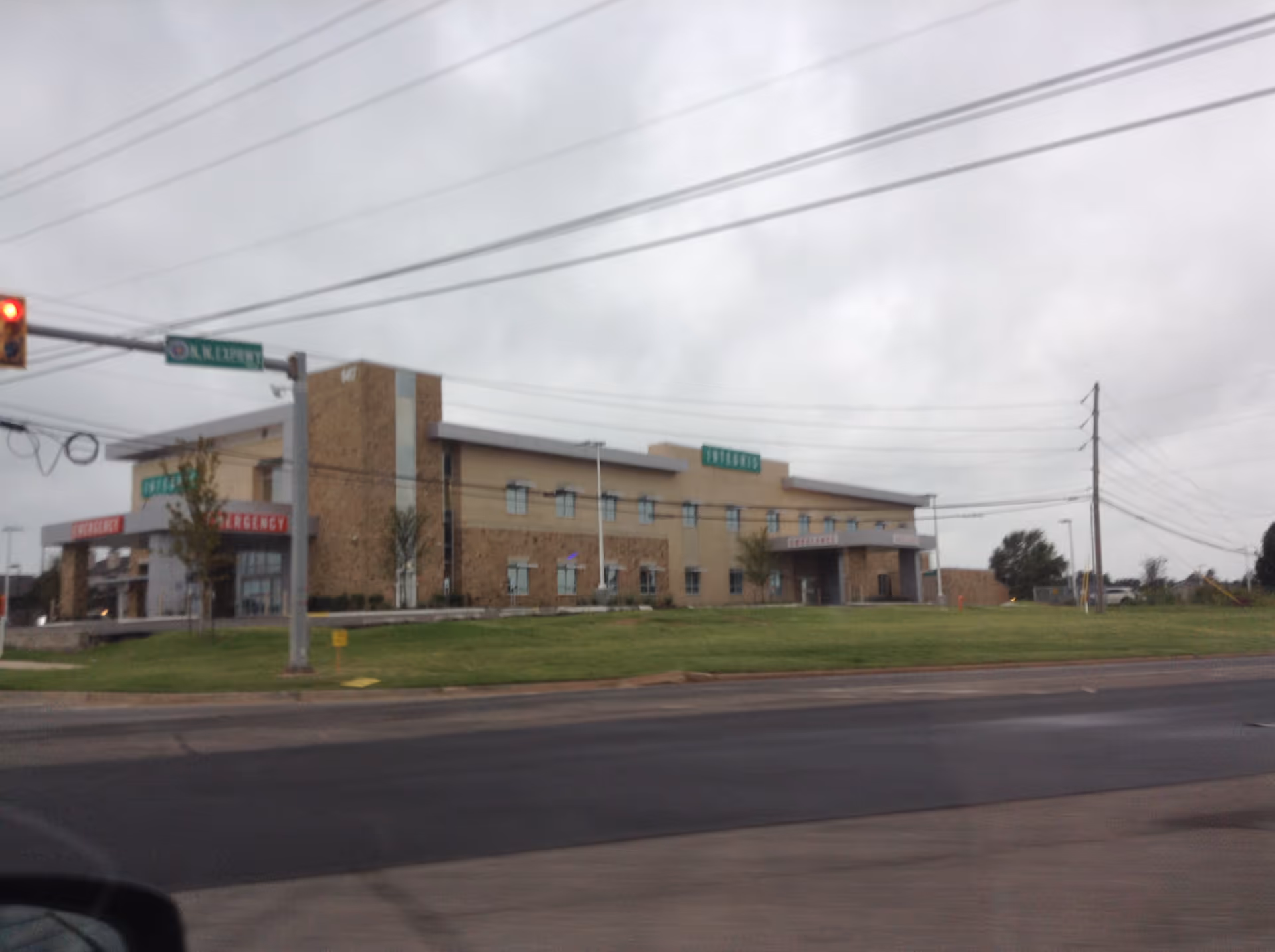 Exterior view of a hospital building with emergency entrance and street signs.
