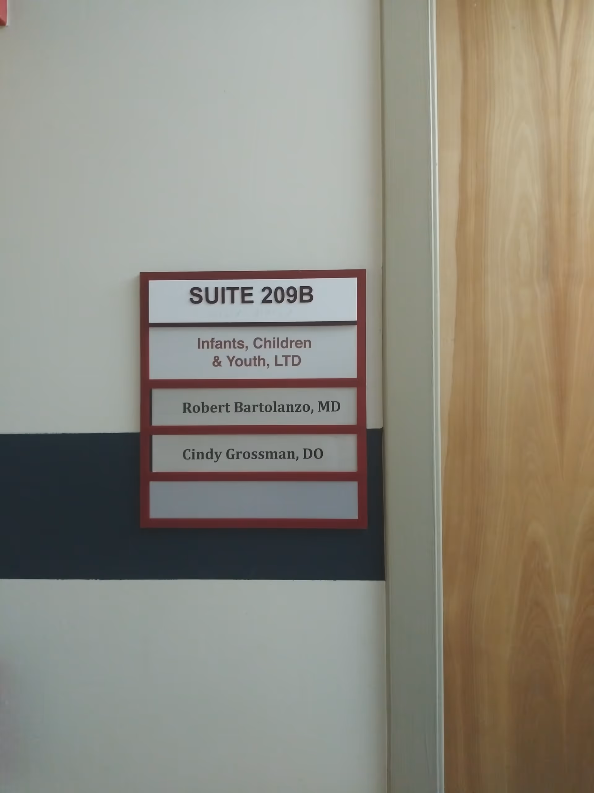 Interior hallway features a red-framed sign listing Suite 209B and names.