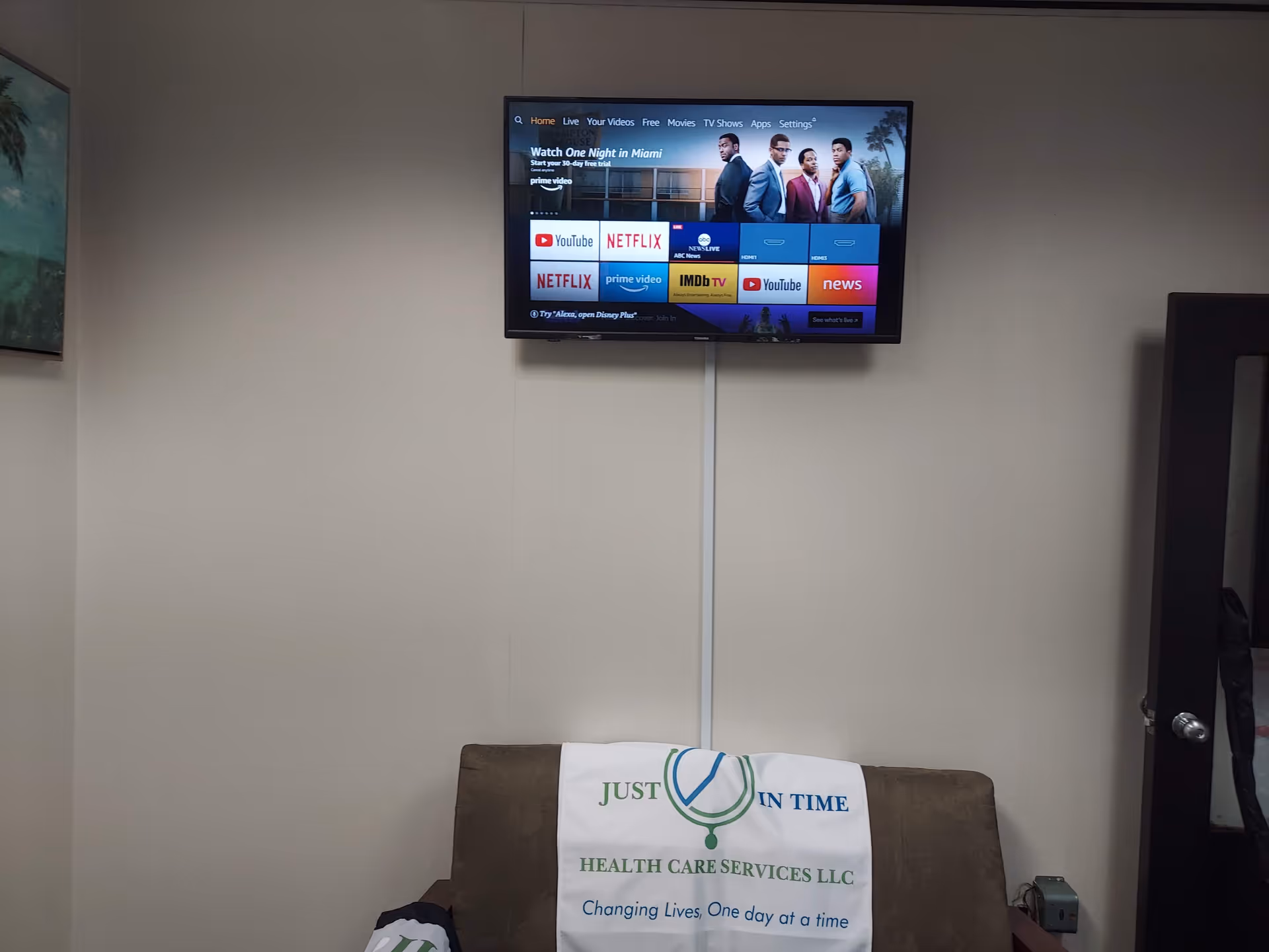 TV mounted on wall above sofa with a Just in Time banner.