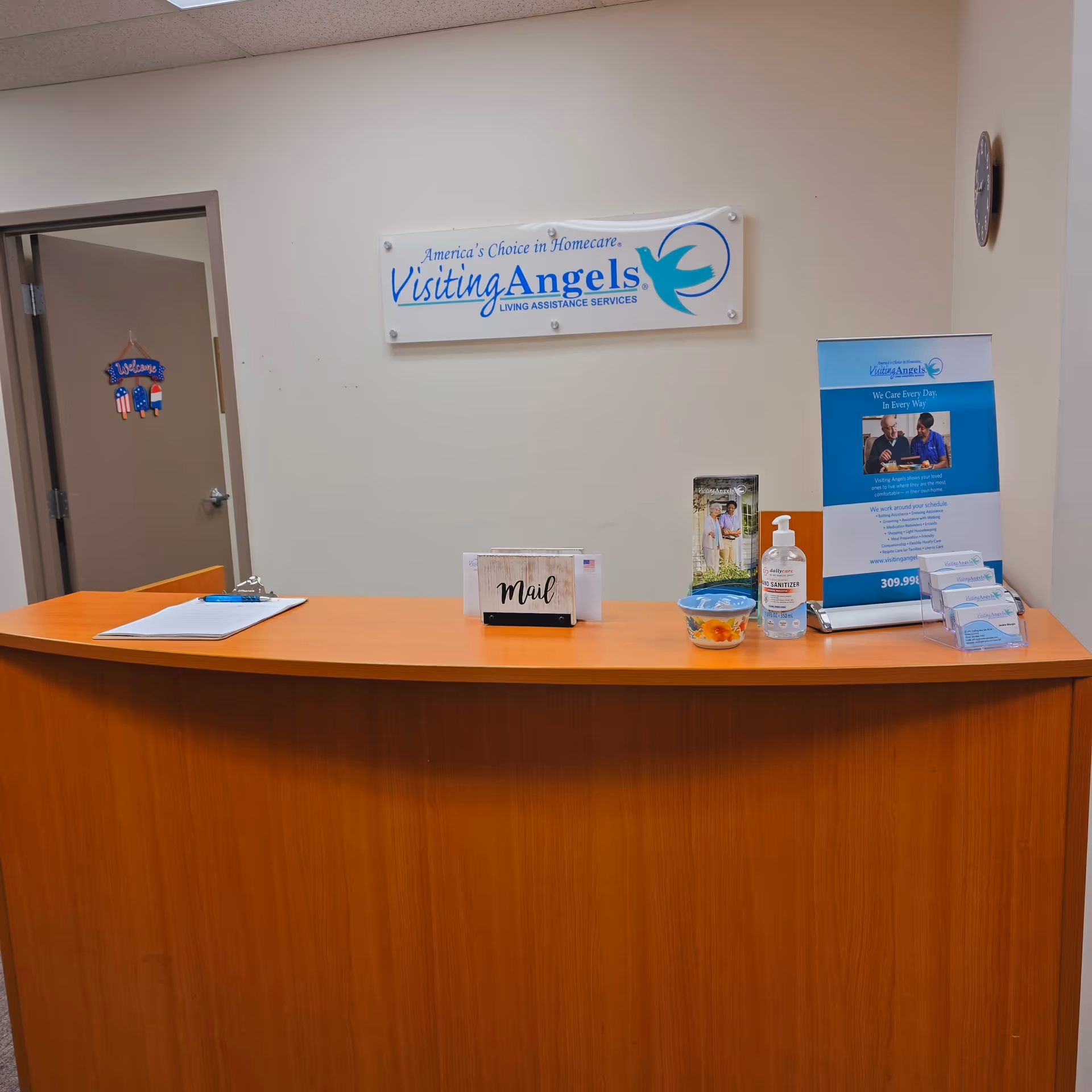 Reception desk in a neutral lobby with Visiting Angels sign on wall.