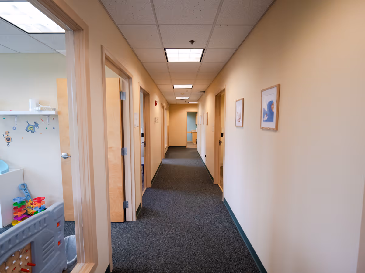 Narrow interior hallway of a senior facility with doors and framed art.