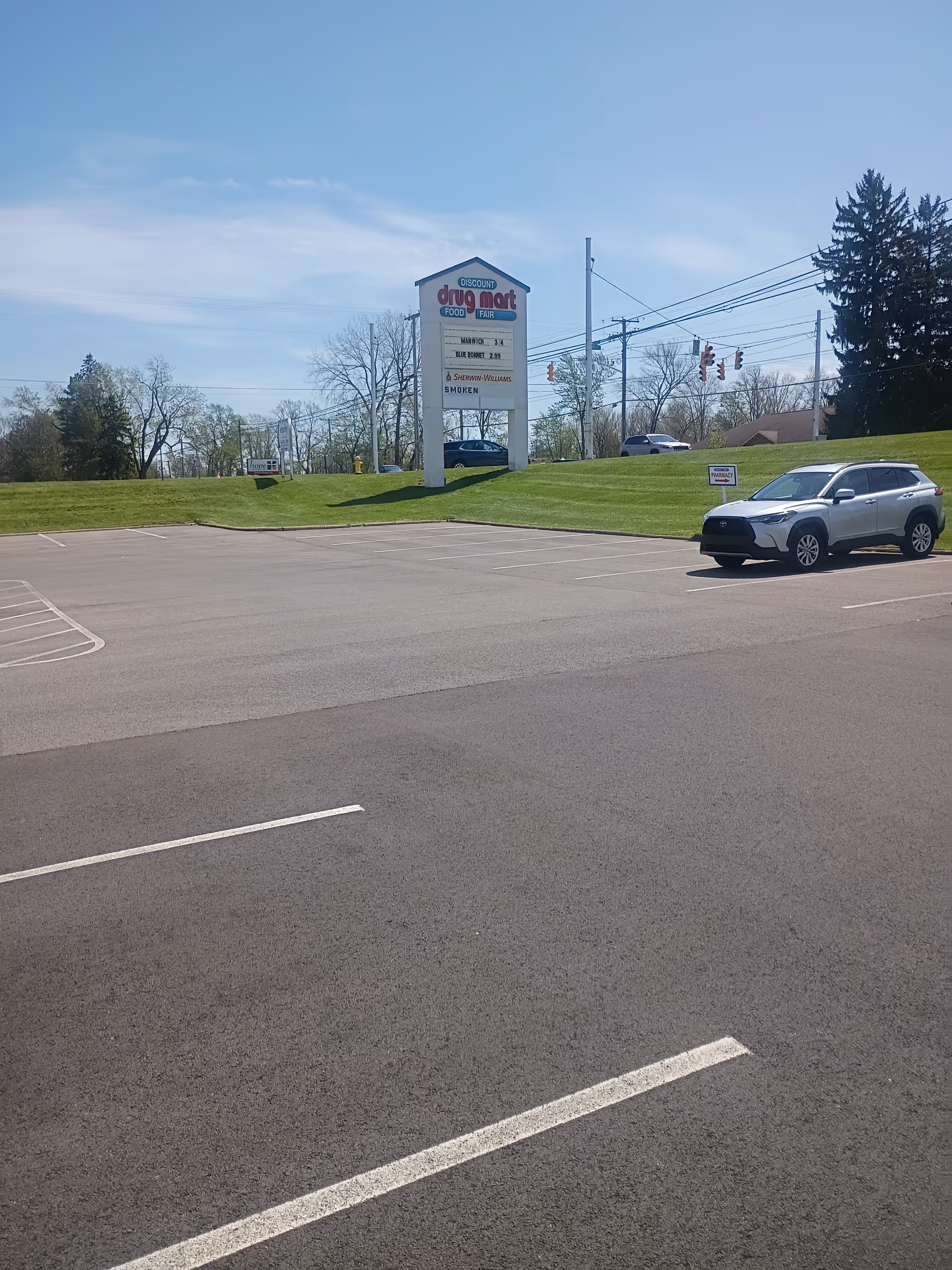 Parking lot in front of Discount Drug Mart with a large sign and silver SUV.