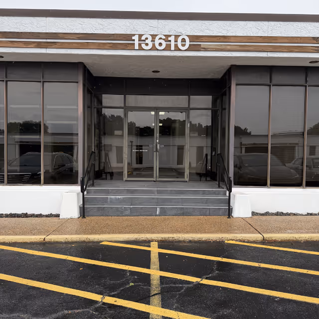 Exterior view of a building entrance with glass doors and the number 13610.