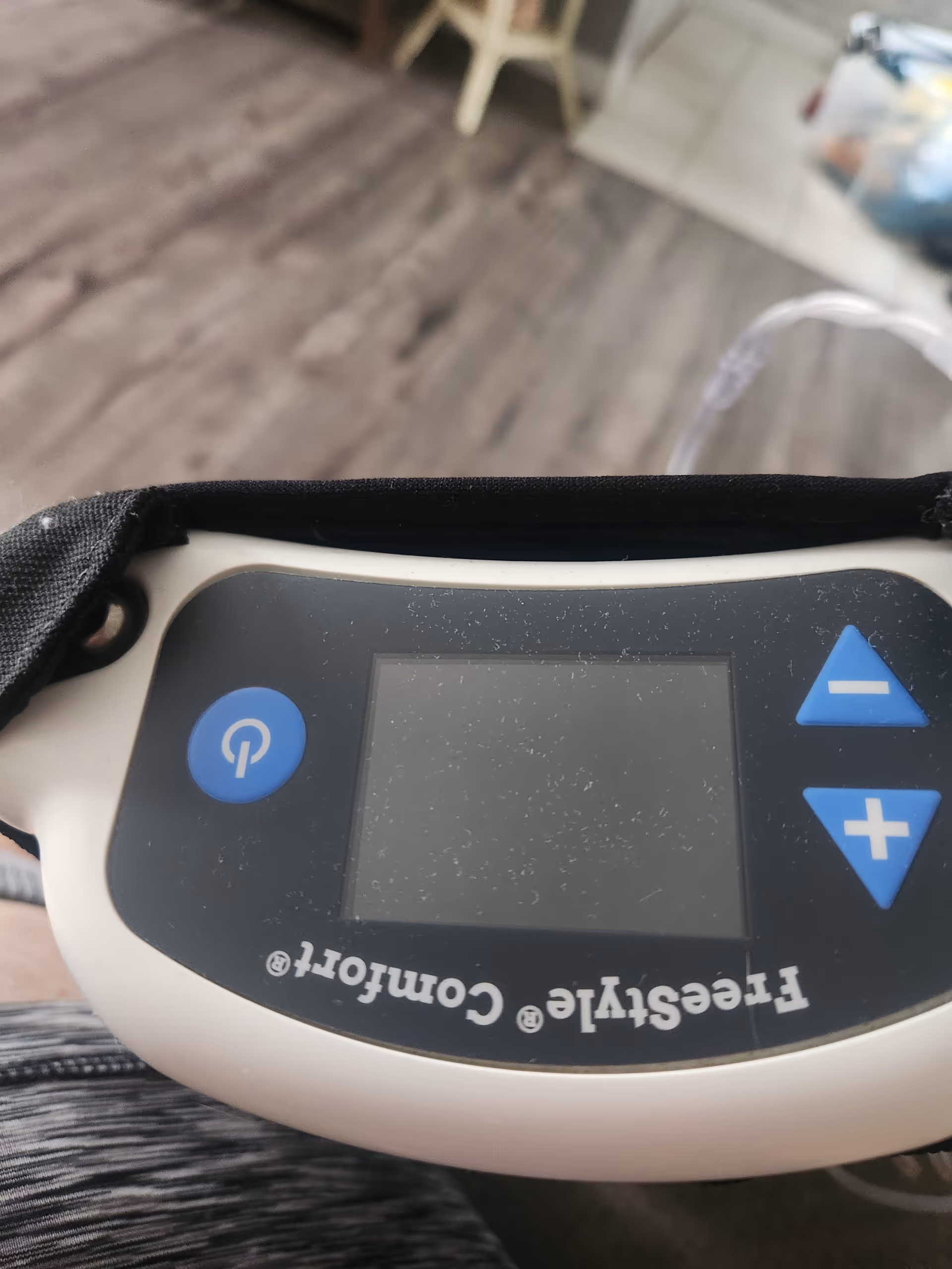 Close-up of a handheld medical controller with power button and up/down arrows.