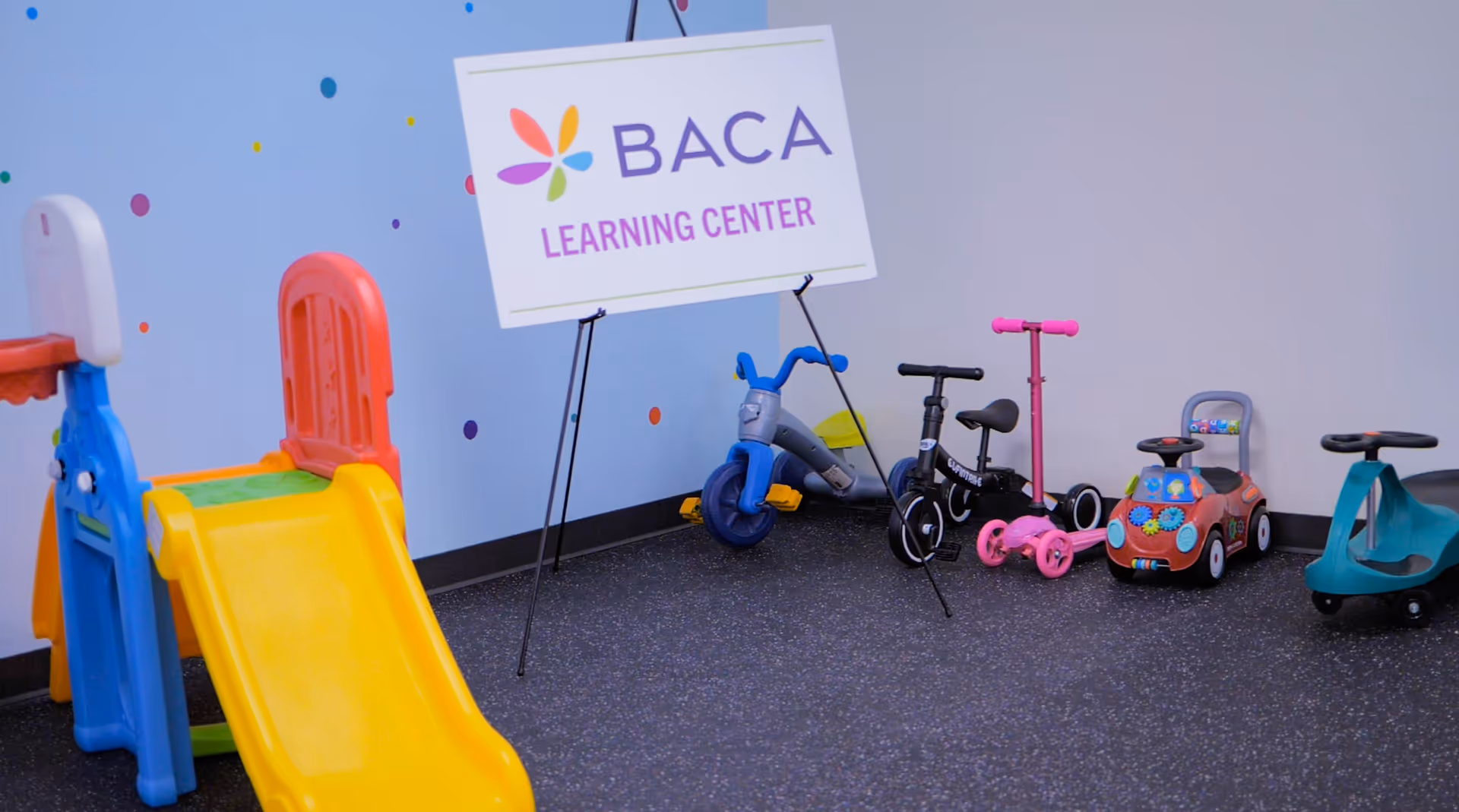 Bright indoor play area with colorful slide and toy cars at BACA Learning Center