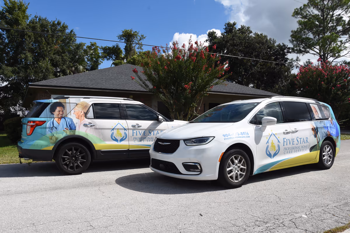Two branded Five Star vans parked in front of a building with trees and flowering shrubs.