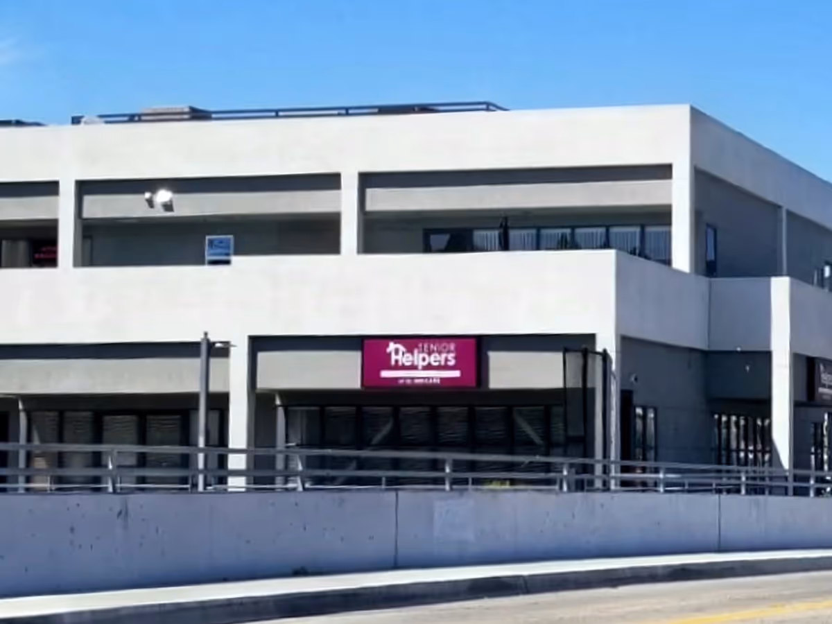 Exterior view of a modern Senior Helpers facility with a maroon storefront sign.