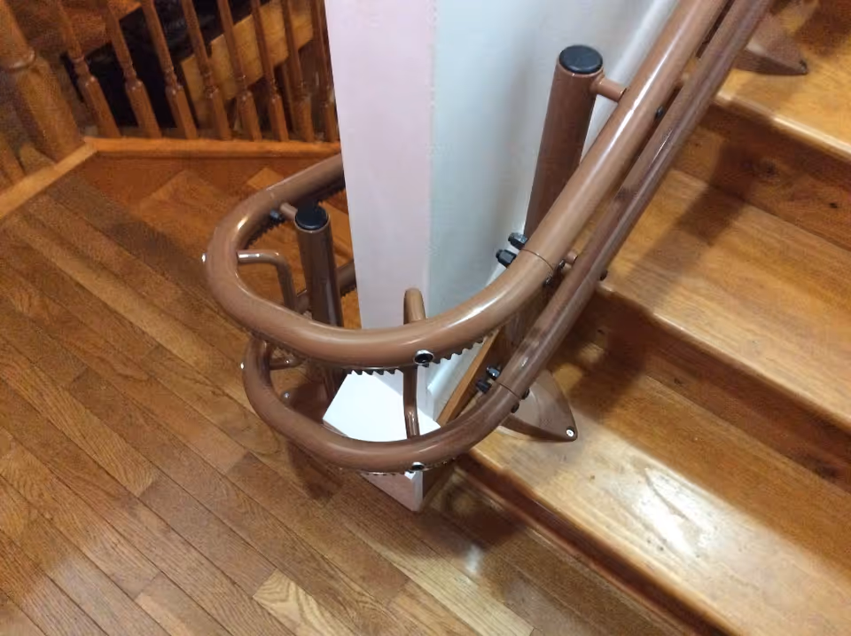Brown curved stair railing with wooden steps in a multi-level interior.